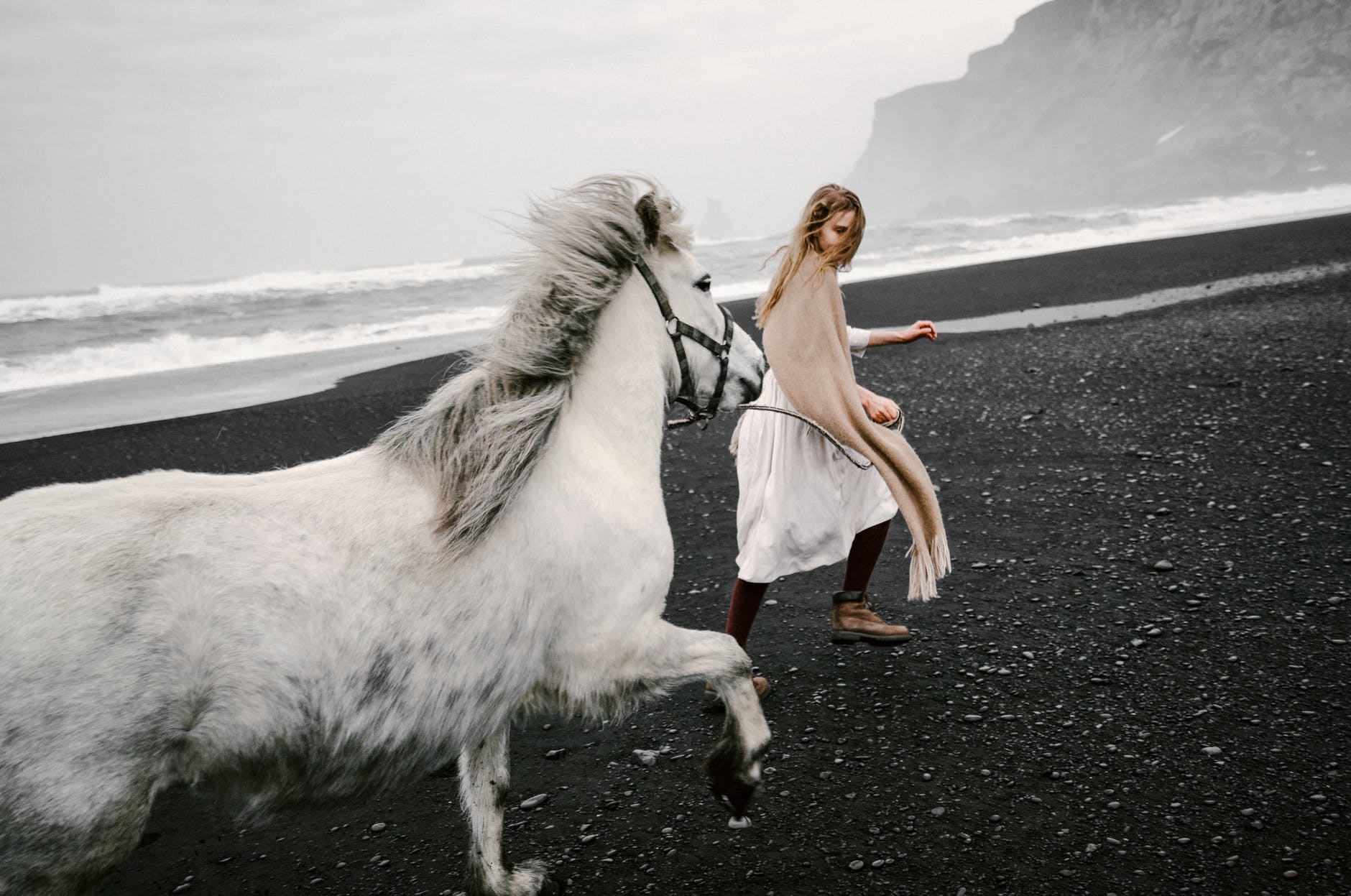 inspired teen girl leading horse on black sand beach