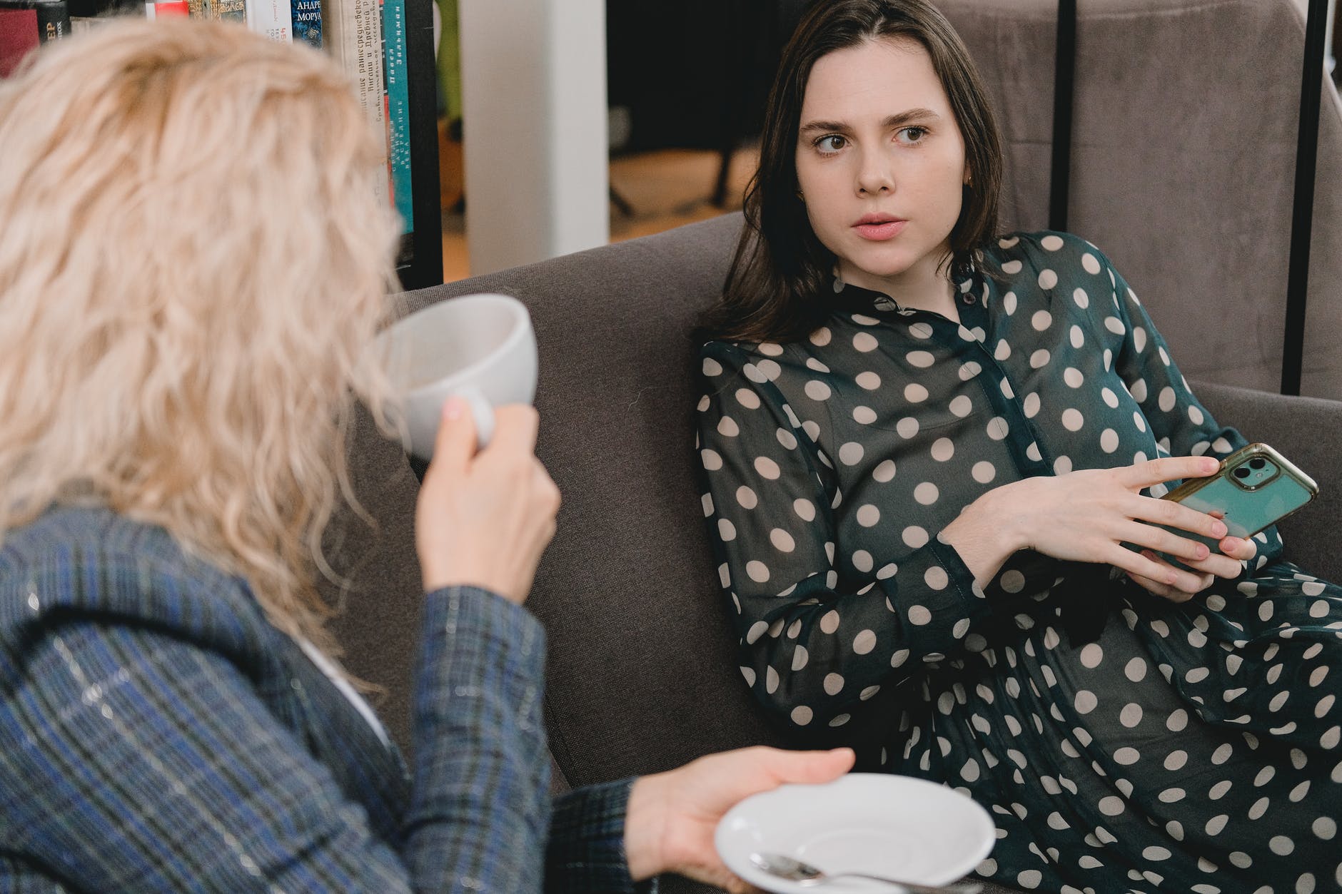 young stylish ladies gossiping and drinking coffee in cafe