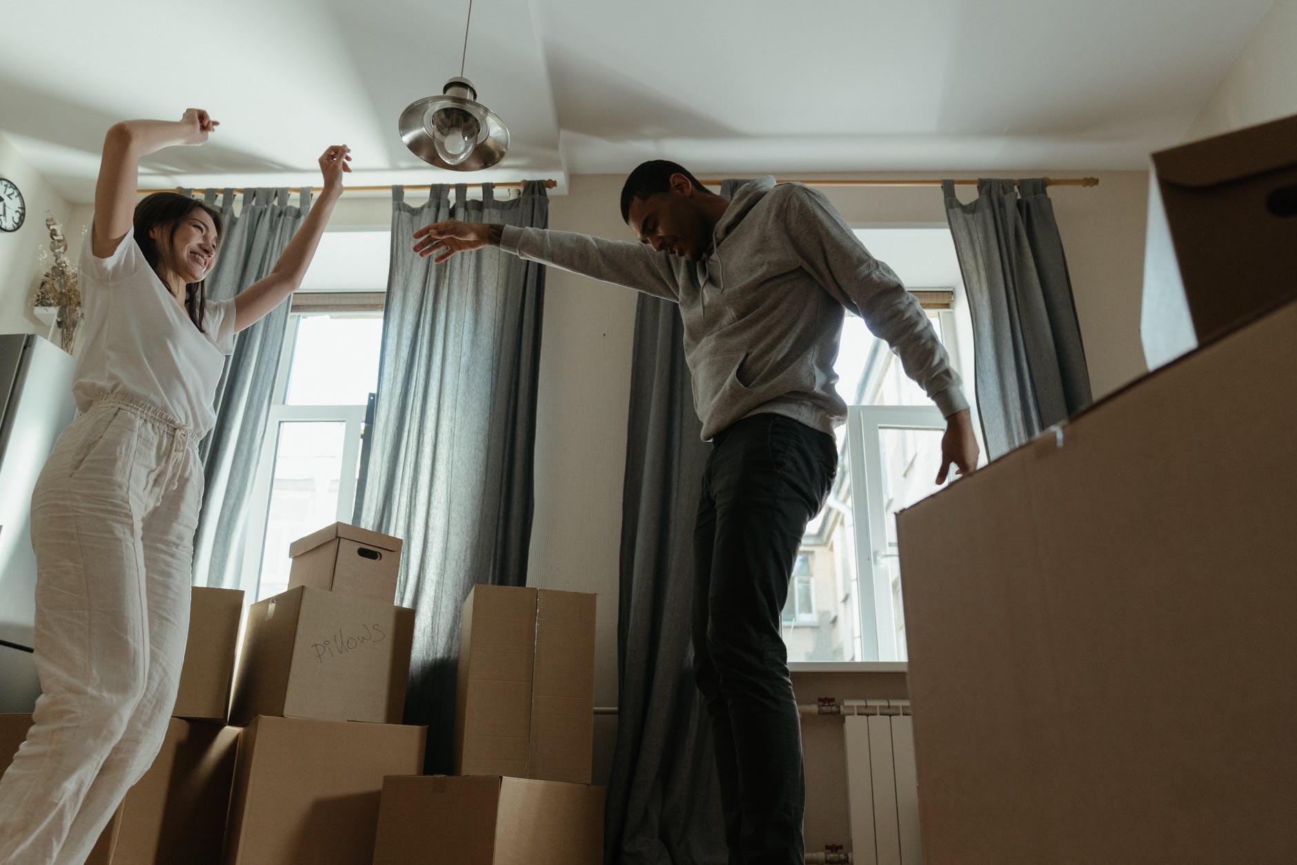 man in gray long sleeve shirt and black pants standing beside brown cardboard boxes