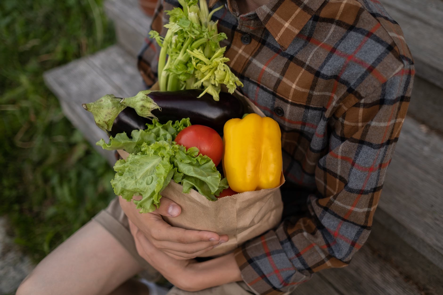 teenage boy holding paper bag with vegetables