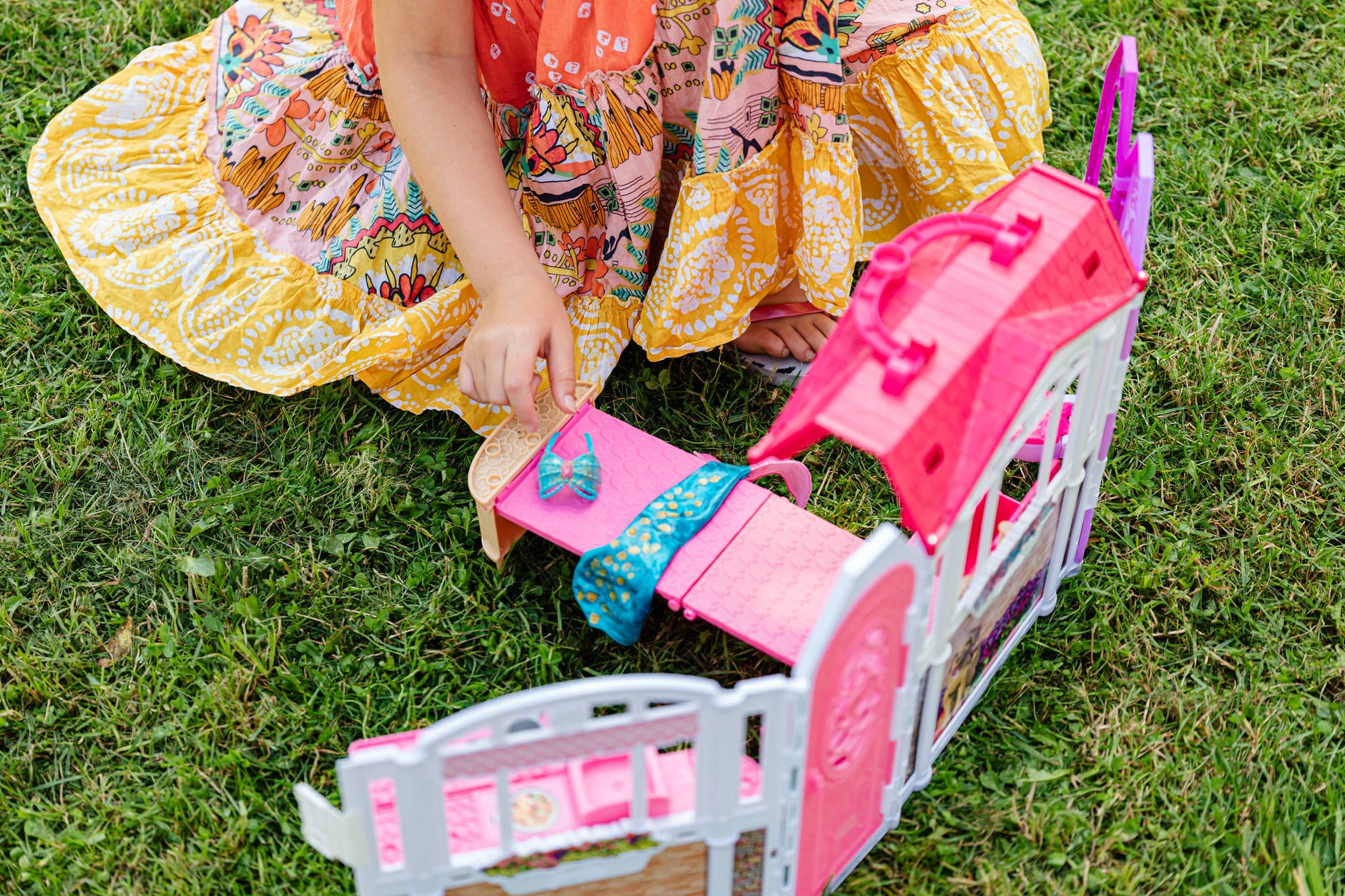 girl in floral dress playing mini bedroom toy